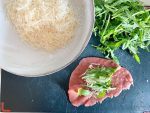 Mettete su di un tagliere le fettine di carpaccio e riempitele con mezzo cucchiaio di grana e poca rucola.